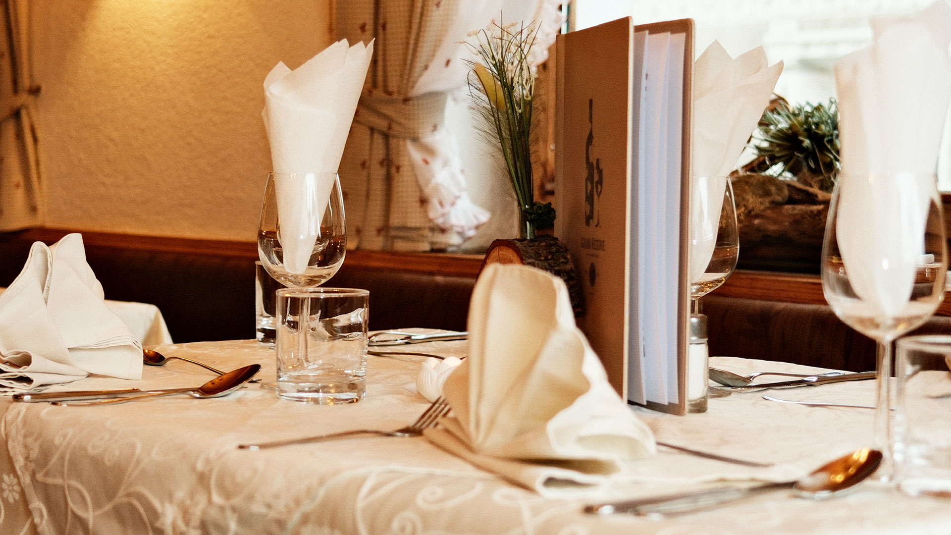 Stilvoll gedeckter Restauranttisch mit Weingläsern, Servietten und Menükarte