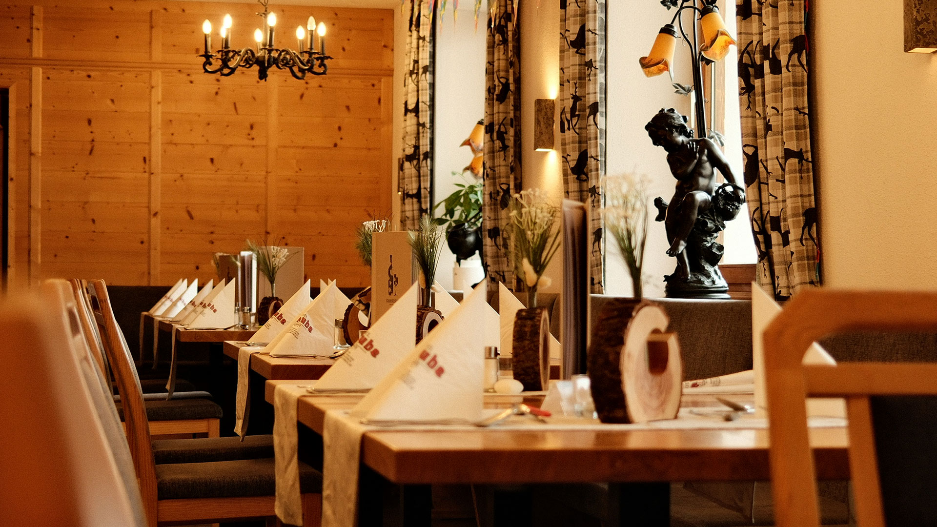 Eleganter Restaurantbereich mit Fensterplätzen, warmem Licht und liebevoll gedeckten Tischen