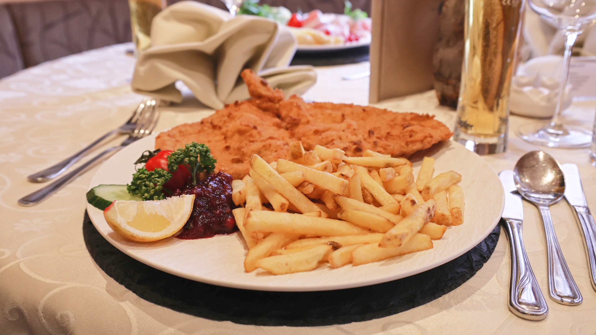 Warme Hauptspeise mit paniertem Fleisch, Pommes und Beilagen auf einem Teller im Hotel Traube in Fließ.