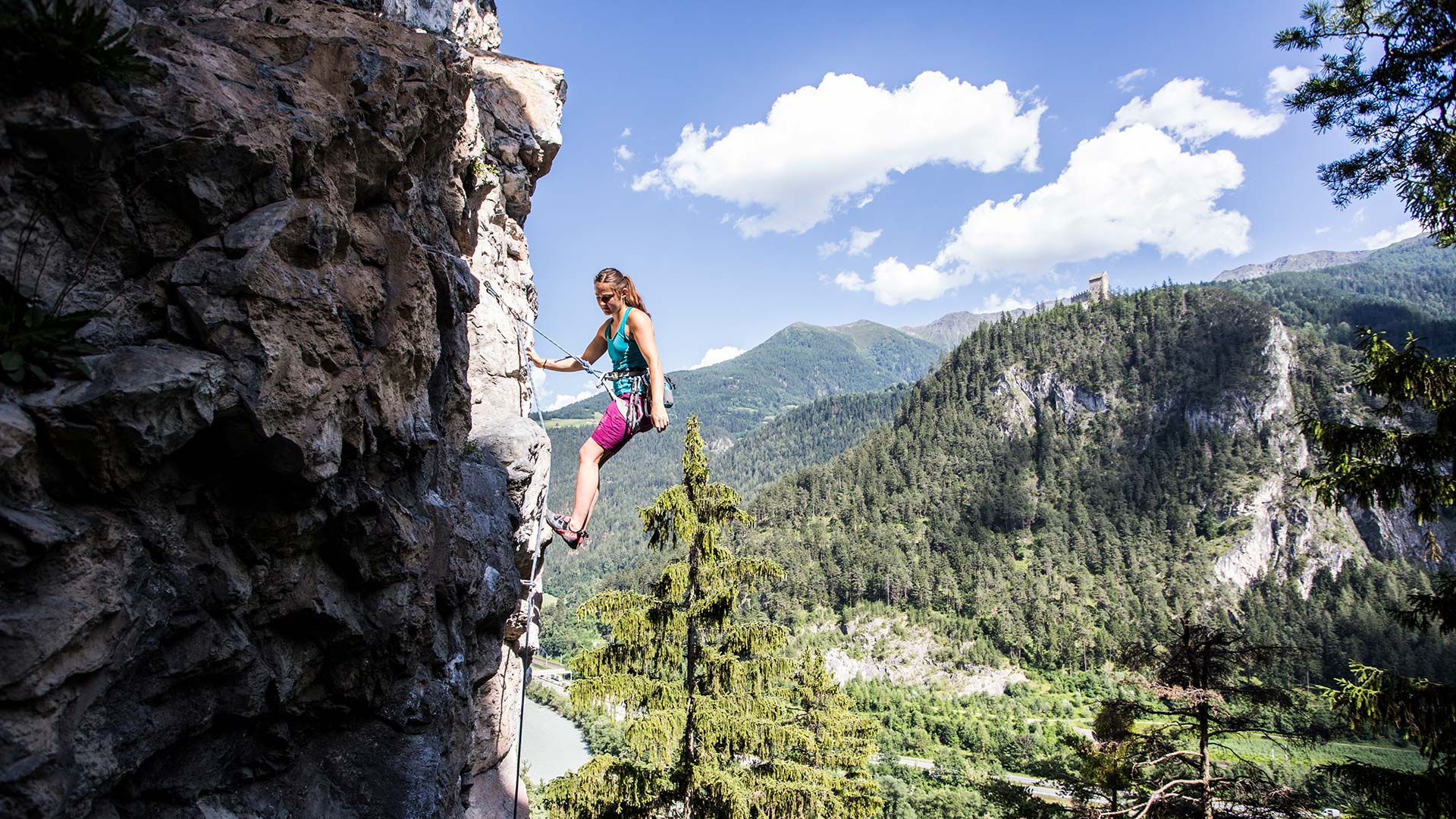 Frau beim Klettern am Felsen mit Bergpanorama in Tirol