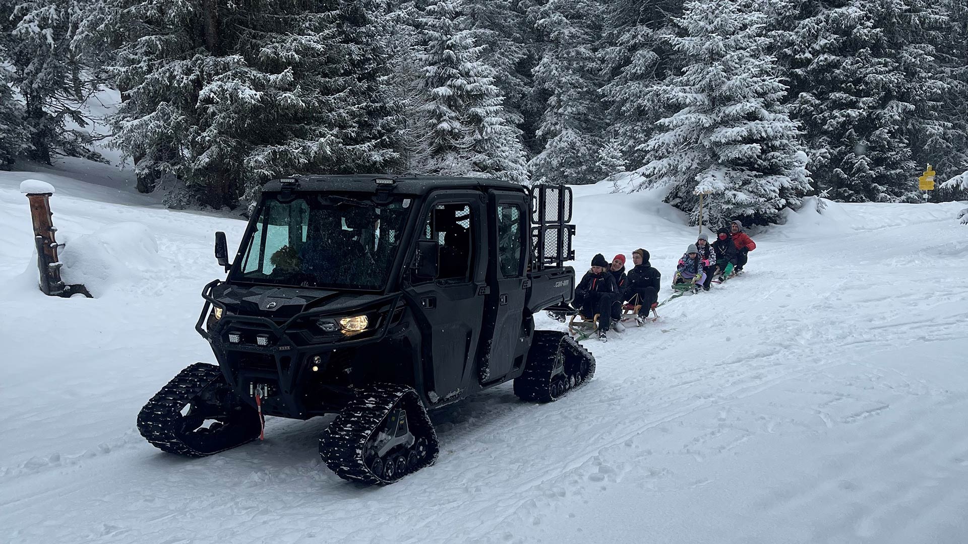 Quad in winterlicher Landschaft mit angehängten Rodeln